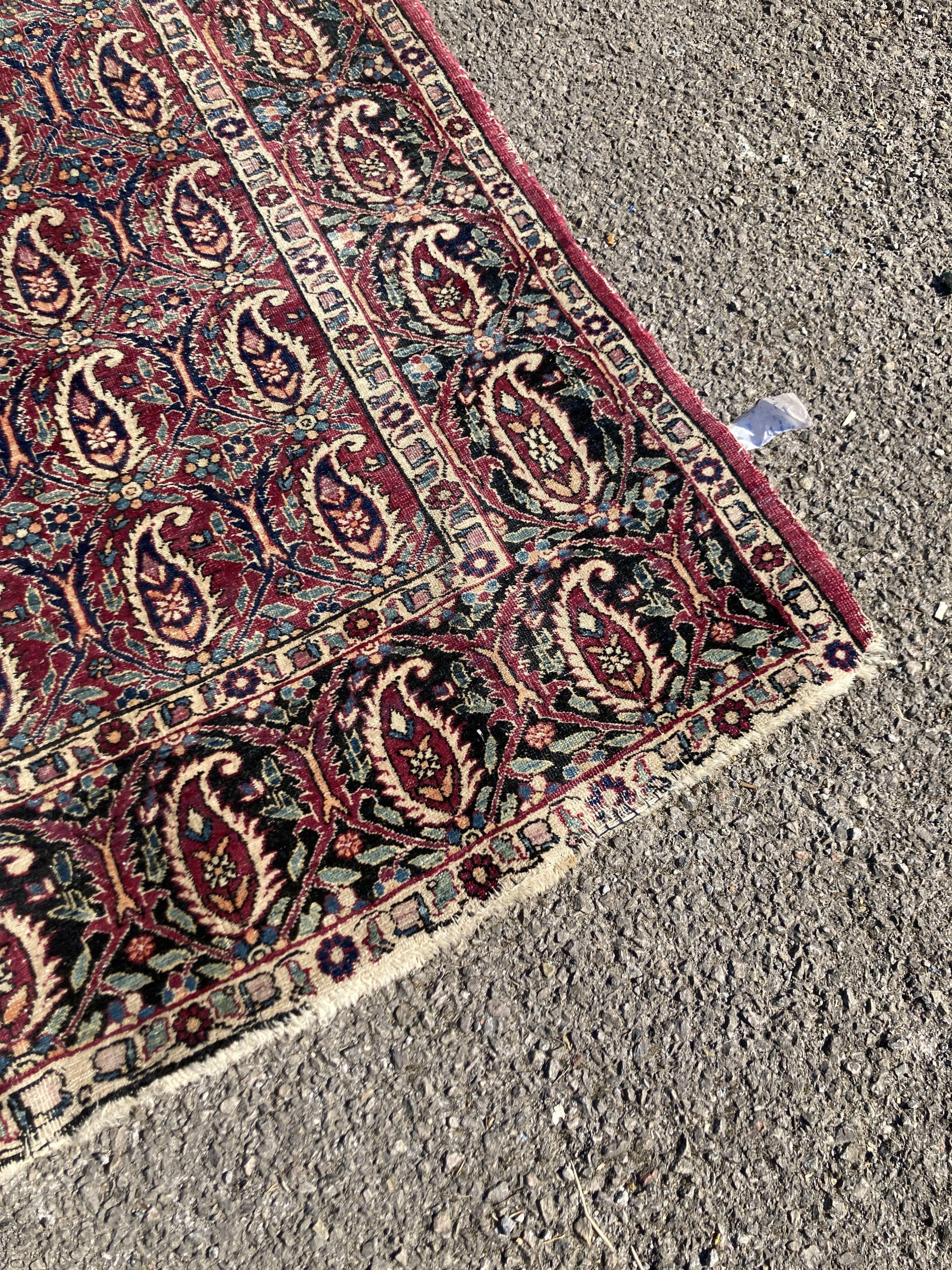 An early 20th century Persian Senneh red ground rug woven with rows of Boteh 218 x 130 cms